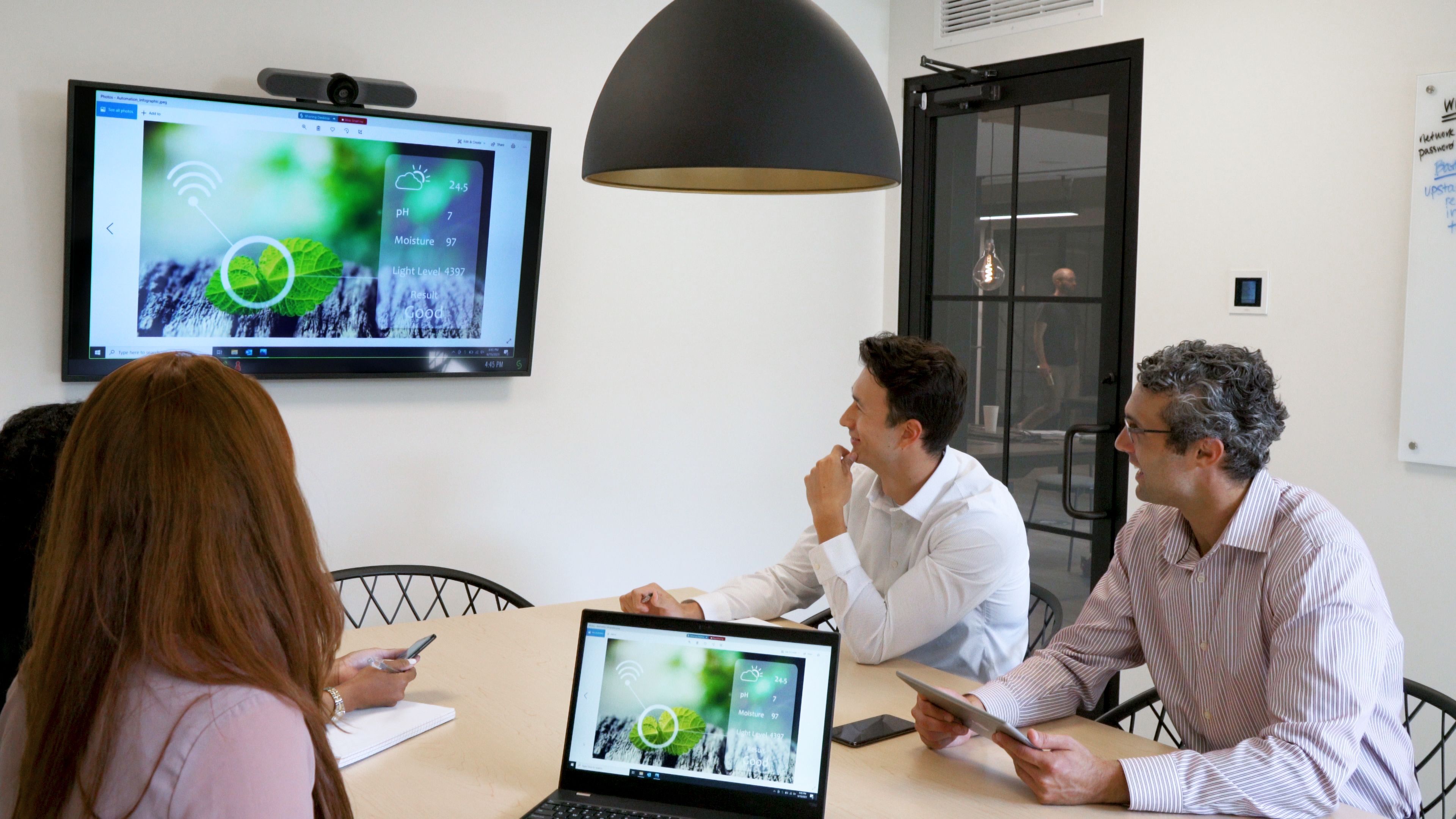 Three workers who use a Solstice to share content in a small meeting room